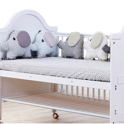 Dans le lit de bébé, plusieurs éléphants rembourrés forment un tour de lit bébé doux et protecteur