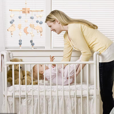 maman dépose son bébé dans le lit mobile musique bébé
