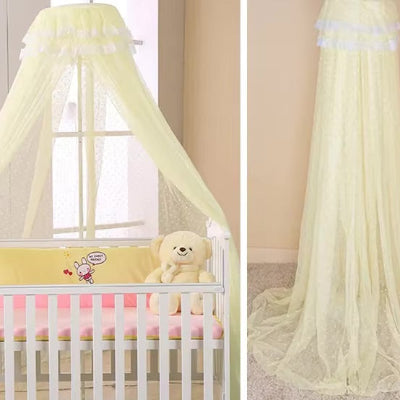 Une moustiquaire de lit jaune légère et élégante en dentelle recouvre un lit bébé blanc tandis qu'elle se déploie gracieusement jusqu'au sol sur le côté, révélant un voile raffine.