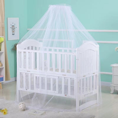 Une moustiquaire lit blanche et légère est suspendue au-dessus d'un lit bébé blanc formant un voile protecteur qui enveloppe délicatement le berceau.