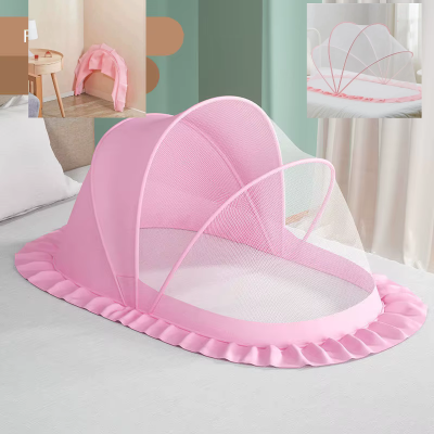 Une moustiquaire pour lit bébé de couleur rose en forme de dôme est posée sur le lit