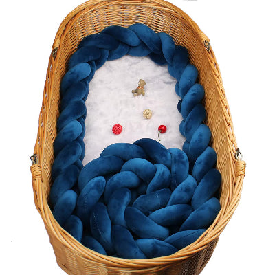 Un panier en osier accueille une tresse de lit cabane bleu marine transformant l'espace en un cocon douillet et sécurisant pour le bébé.