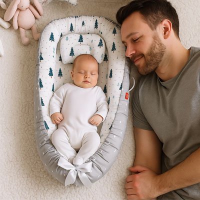 le papa dort avec son bébé qui dort dans son réducteur de lit bébé