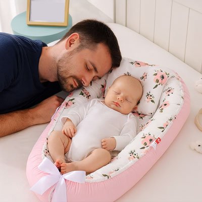 le papa endormi avec son bébé qui dort dans son réducteur de lit bébé
