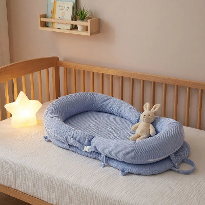 reducteur de lit bebe WeedgePood™ bleu déposé dans le lit avec doudou lapin et veilleuse sur le côté.
