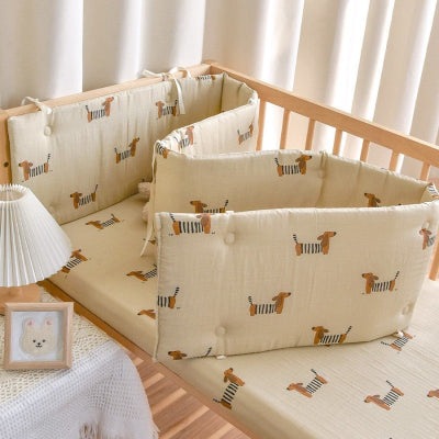 Un tour de lit bebe beige orne de motifs de petits chiens entoure le lit bébé en créant une protection douce et modulable.