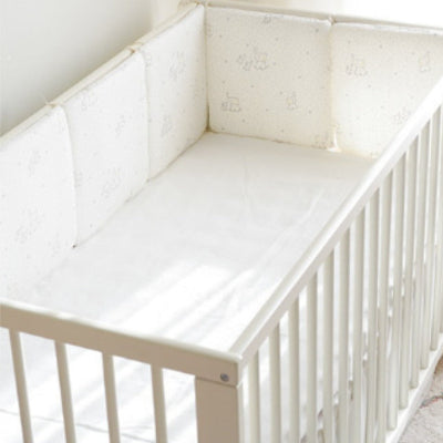 Le tour de lit bébé complet blanc rembourré, décoré d’éléphants, de petites étoiles et de lignes de points, apporte une sensation de confort et de sécurité.