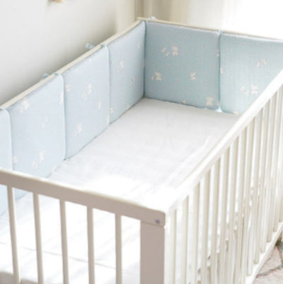 Un tour de lit bébé complet bleu rembourré orné d’éléphants, de petites étoiles et de lignes de points, offrant confort et protection.