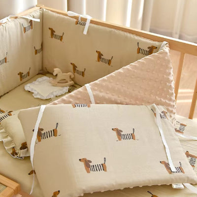 Un tour de lit bebe rembourre beige et décoré de chiens enroule et installe pour sécuriser l'intérieur d'un lit bébé.