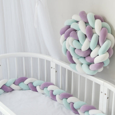 Tresse de lit 3 m aux teintes pastel violet, blanc et bleu entoure le lit bébé blanc avec une seconde tresse enroulée en boule fixée au mur pour une décoration douce et harmonieuse.