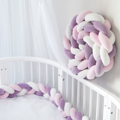 Tresse de lit 3 m aux teintes pastel violet, blanc et rose entoure le lit bébé blanc avec une seconde tresse enroulée en boule fixée au mur