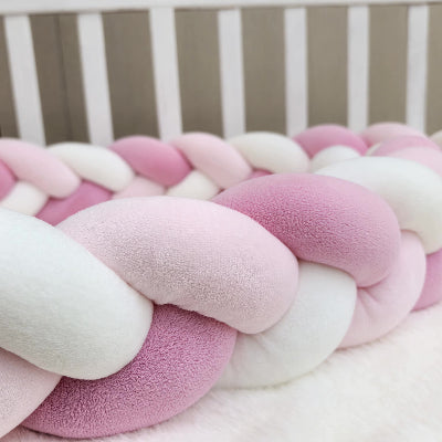 tresse tour de lit aux teintes rose et blanc moelleux installée dans un lit bébé blanc pour offrir une protection douce